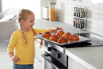 Wall Mural - Little girl with tray of oven baked buns in kitchen