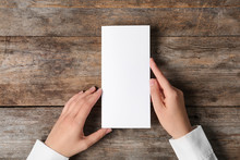 Woman Holding Blank Brochure Mock Up On Wooden Table, Top View