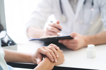 Doctor listening patient explain his symptom and notes to medical record.