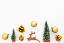 Christmas And New Year Background. Christmas Tree, Gold Pine Cones, Gold Balls And Reindeer On White Paper. Creative Flat Lay, Top View