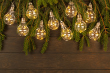 Christmas Lights Garland With Green Fir Tree On Wooden Background