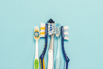 Wall Mural - Several different used toothbrushes on a blue background. Toothbrush change concept, oral hygiene, big and friendly family. Flat lay, top view