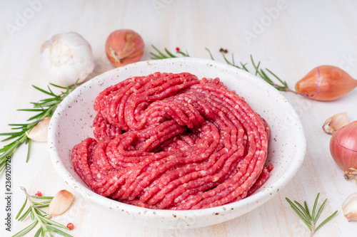 Foto Mince beef, ground meat with ingredients for cooking on white wooden rustic tabl