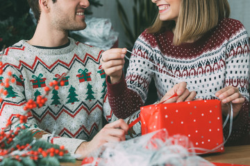 Wall Mural - Young woman and man wrap Christmas gift