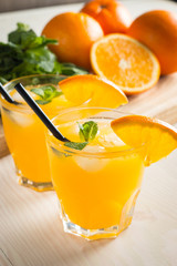 Photo of fresh orange juice in the glass jar. Summer healthy organic drink concept. Cold beverages with ice and orange fruits.