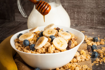 Healthy breakfast concept with oat flakes and fresh berries on rustic background. Food made of granola and muesli. Healthy banana smoothie with blackberries, honey and milk.