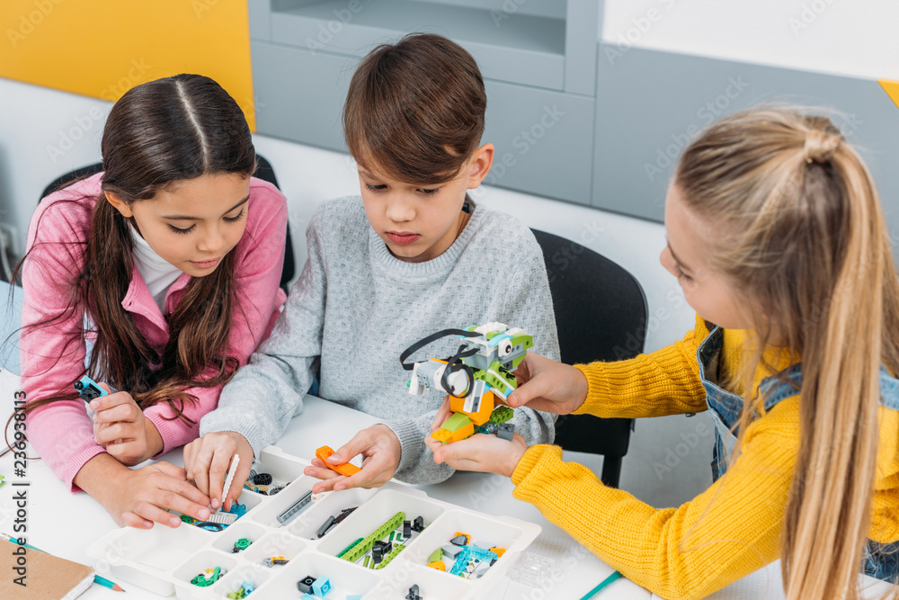 attentive classmates discussing ideas while making robot at STEM ...