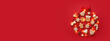 Creative Christmas Ball Made Of Iced Gingerbread Cookies, Anise Stars, Berries, Orange Chips, Decorated Red Ribbon Bow On Red Background. New Year Banner. Top View.