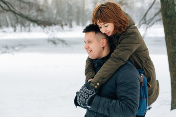 Winter portrait of young beautiful happy smiling couple outdoors. Christmas and winter holidays. Man and woman in snowy park