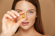 © Drobot Dean - Beauty image of adorable shirtless woman 20s holding vitamin pill, isolated over beige background