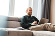 © Drobot Dean - Concentrated young bearded man sitting in home using laptop computer.