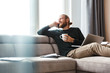 © Drobot Dean - Handsome young bearded man sitting in home using laptop computer talking by phone.