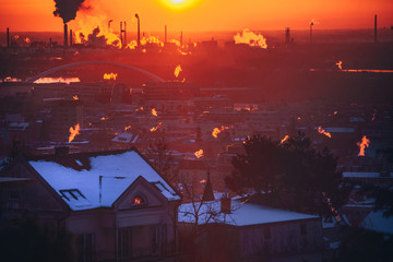 Winter morning in the city. Orange smoke from chimney. Industrial Factory and smoke in background. Ecology, pollution concept photo. Bratislava, Slovakia, Europe.