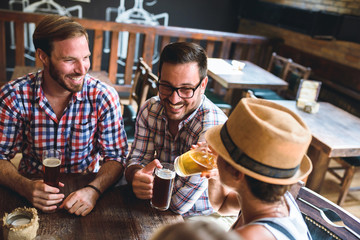 Wall Mural - Young cheerful people in the beer pub drinking and having good time