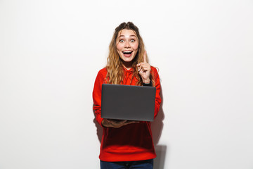 Sticker - Image of charming woman 20s wearing red sweatshirt holding laptop, isolated over white background