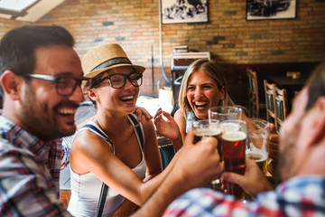 Young cheerful people in the beer pub drinking and having good time