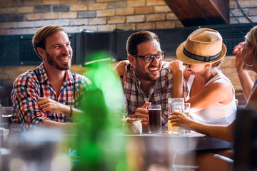 Wall Mural - Happy friends having fun at bar - Young trendy people drinking beer and laughing together