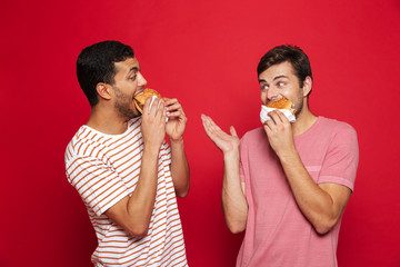 Two cheerful men friends standing isolated over red