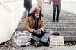 © Halfpoint - Homeless beggar man sitting outdoors in city asking for money donation.