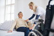 © Halfpoint - A health visitor talking to a senior woman sitting on bed at home.