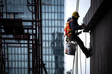 Construction worker wearing safety harness and safety line working at high place