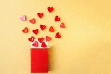 Wall Mural - Valentine's day concept. gift for Valentine's Day, a red box with sweet hearts on a gold background. Pictures of Love. selective focus