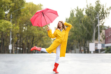 Wall Mural - Happy young woman with red umbrella in city on rainy day