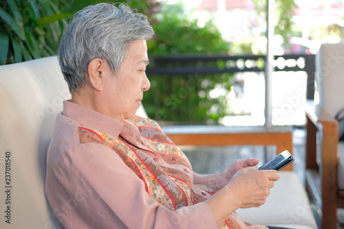 Fotografia asian elder woman holding mobile phone at home