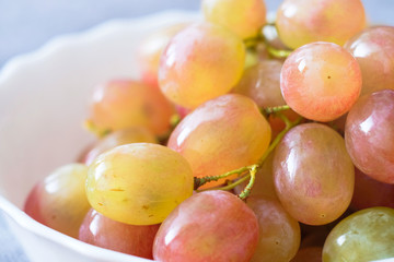 Grapes in a porcelain plate. Ripe pink Muscat grapes.