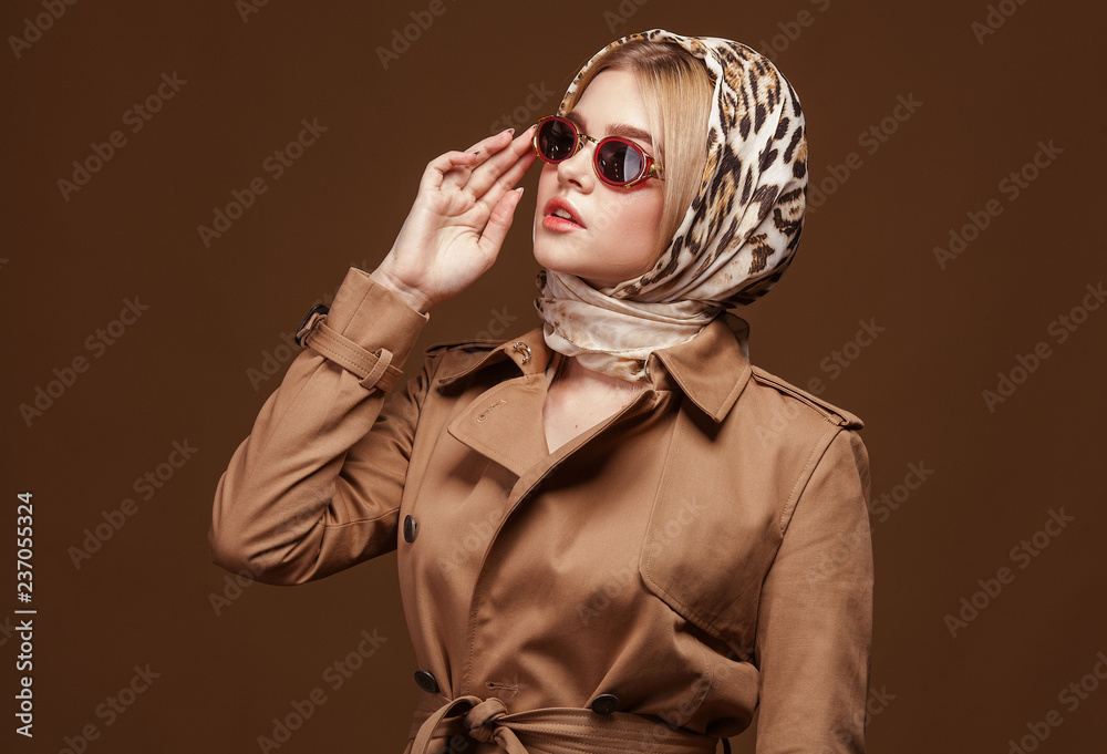 Portrait of young beautiful woman in trendy trench coat over beige ...