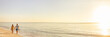 © Maridav - Beach couple walking on beach watching sunset tropical landscape banner panoramic background. Summer holidays destination panorama. relaxing vacation - travel tourists.