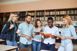 © alfa27 - Portrait of multiethnic diverse friends pupils looking at page of interesting book in college library