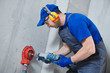 © Kadmy - electrician at work. boring hole for electric outlet by power tool drill.