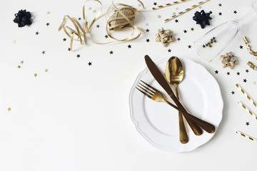 Wall Mural - New Year, Christmas styled glamorous black and gold table setting with plate, goldenware, confetti stars and champagne glass. Party decoration, flat lay, top view. Empty space. Restaurant menu concept