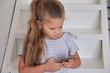 © filirochka - Girl using phone on stairs at home