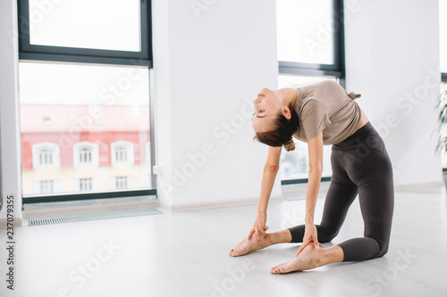 Fotografia Young attractive sporty woman practicing yoga with bent back