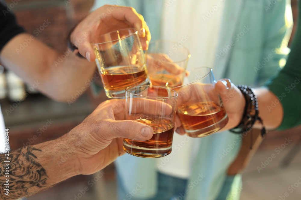 Friends toasting with glasses of whiskey indoors, closeup - obrazy, fototapety, plakaty 