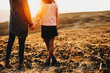 © Strelciuc - Back view of crop man and woman holding hands while standing on field grass during wonderful sundown in countryside.Crop couple standing in field in evening