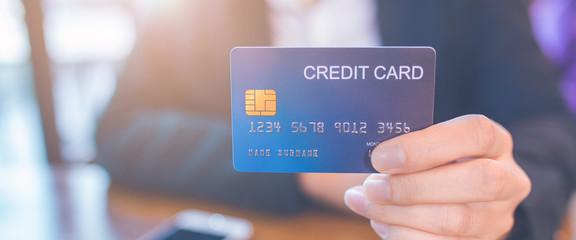 Wall Mural - Business woman hand holds a blue credit card.