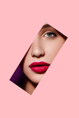 Beautiful woman face in pink paper frame. Plump red lips, blue eyes and clear skin. Fashion and beauty, close up portrait