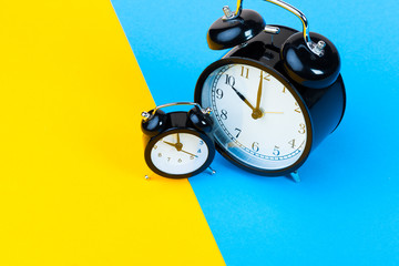 Wall Mural - Black alarm clock on color block yellow and blue background