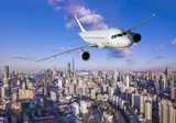 Fototapeta Big Ben - Airplane flying over city business buildings. 