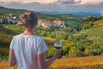 girl holding a glass of red wine looking amazing green vineyards in the italian region of piedmont, 