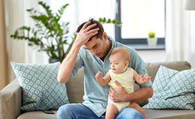 Wall Mural - family, fatherhood and people concept - despaired father with little baby daughter at home