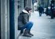 © SB Arts Media - Depressed woman sitting on urban city street overwhelmed and hop