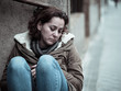 © SB Arts Media - Depressed woman sitting on urban city street overwhelmed and hop