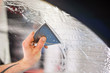 Man squeegeeing water from the window and window tinting film. Professional car window tinting services
