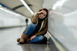 © SB Arts Media - Young desperate adult woman sitting on the ground on subway unde