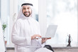 Arabian businessman holding laptop in modern office