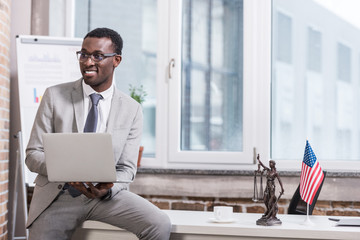 Wall Mural - African american businessman holding laptop in modern office